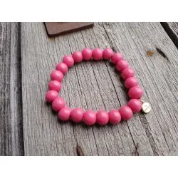 Pinkes Armband aus Holzperlen auf Holzuntergrund