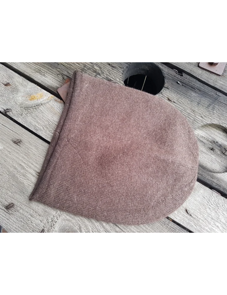 Weiche braune Mütze aus Strickstoff auf Holzhintergrund Weiche braune Mütze aus Strickstoff auf Holzhintergrund