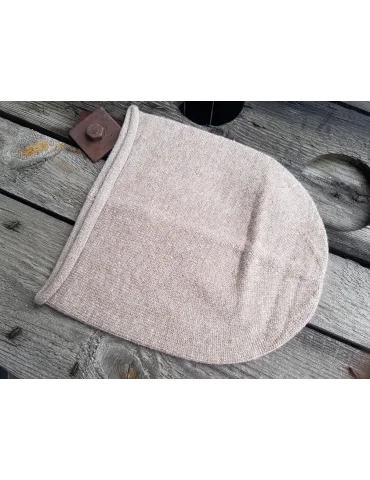 Weiche sandfarbene Mütze aus Strickstoff auf Holzhintergrund