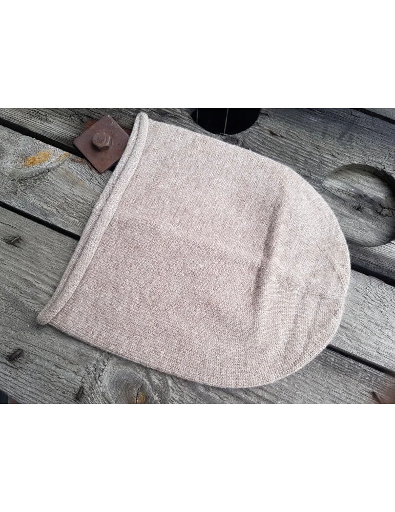 Weiche sandfarbene Mütze aus Strickstoff auf Holzhintergrund Weiche sandfarbene Mütze aus Strickstoff auf Holzhintergrund