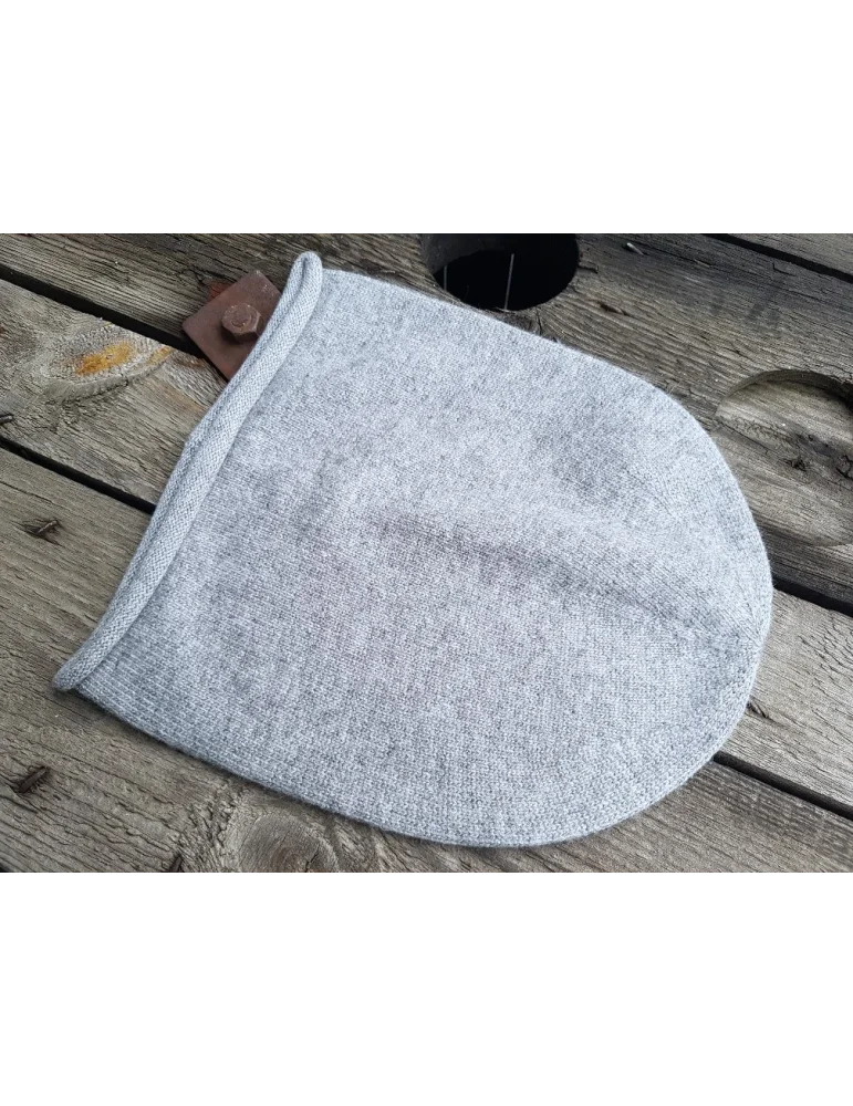 Weiche mittelgraue Mütze aus Strickstoff auf Holzhintergrund Weiche mittelgraue Mütze aus Strickstoff auf Holzhintergrund