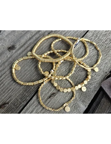 Viele goldfarbene Armbänder auf einem Holzuntergrund