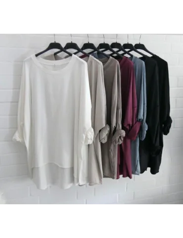 Viele bunte Shirts auf einer Stange vor weißer Wand