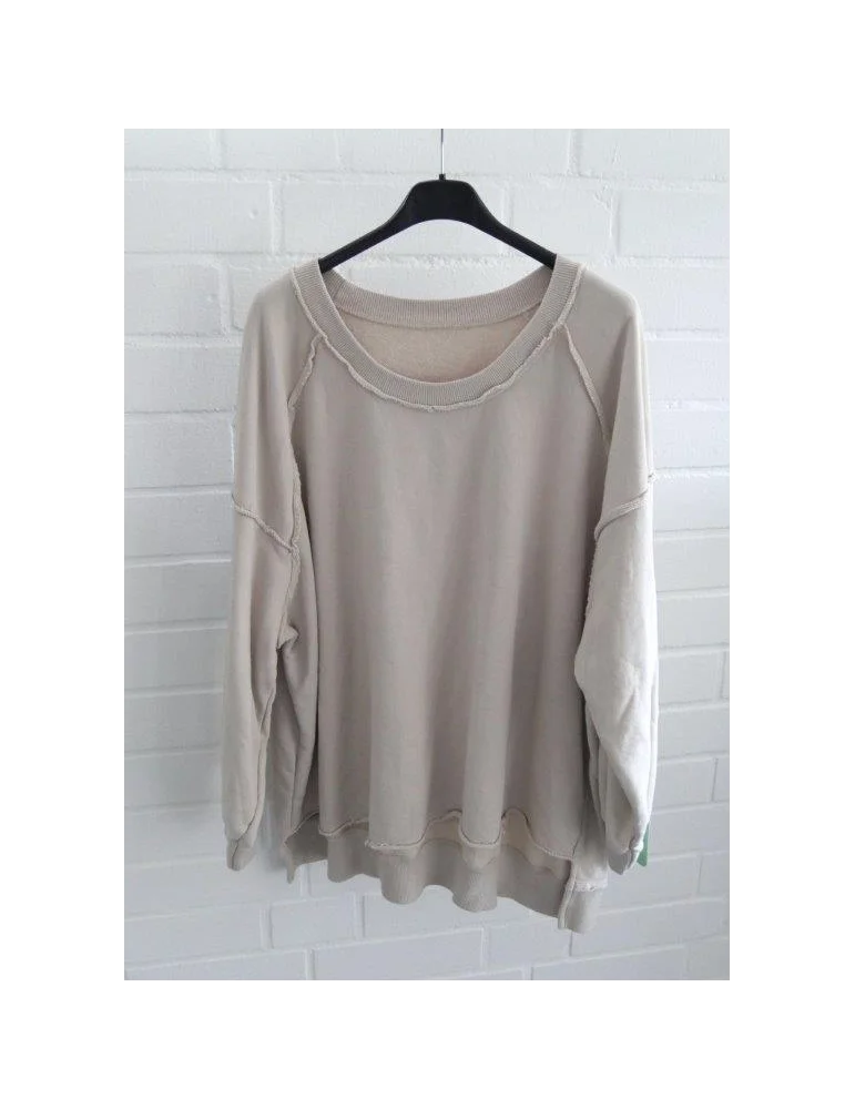 Beiges Oversized Sweatshirt mit Raglanärmeln und Raw Edges auf Bügel vor weißer Wand.