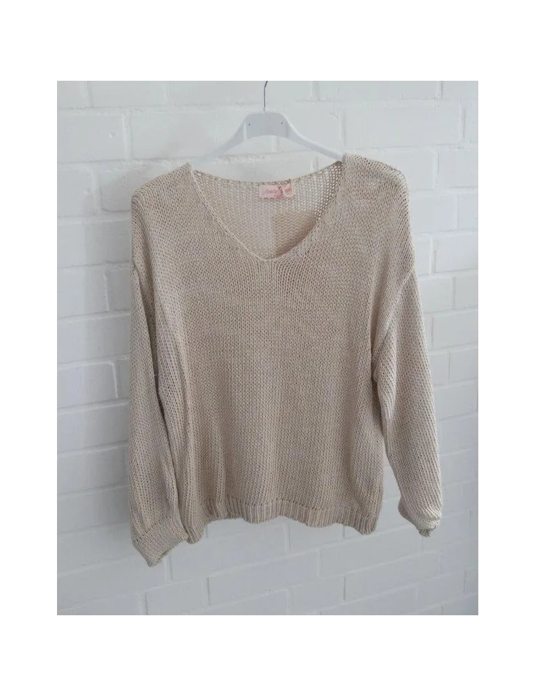 Beige gestrickter Damenpullover mit V-Ausschnitt auf Kleiderbügel vor weißer Wand