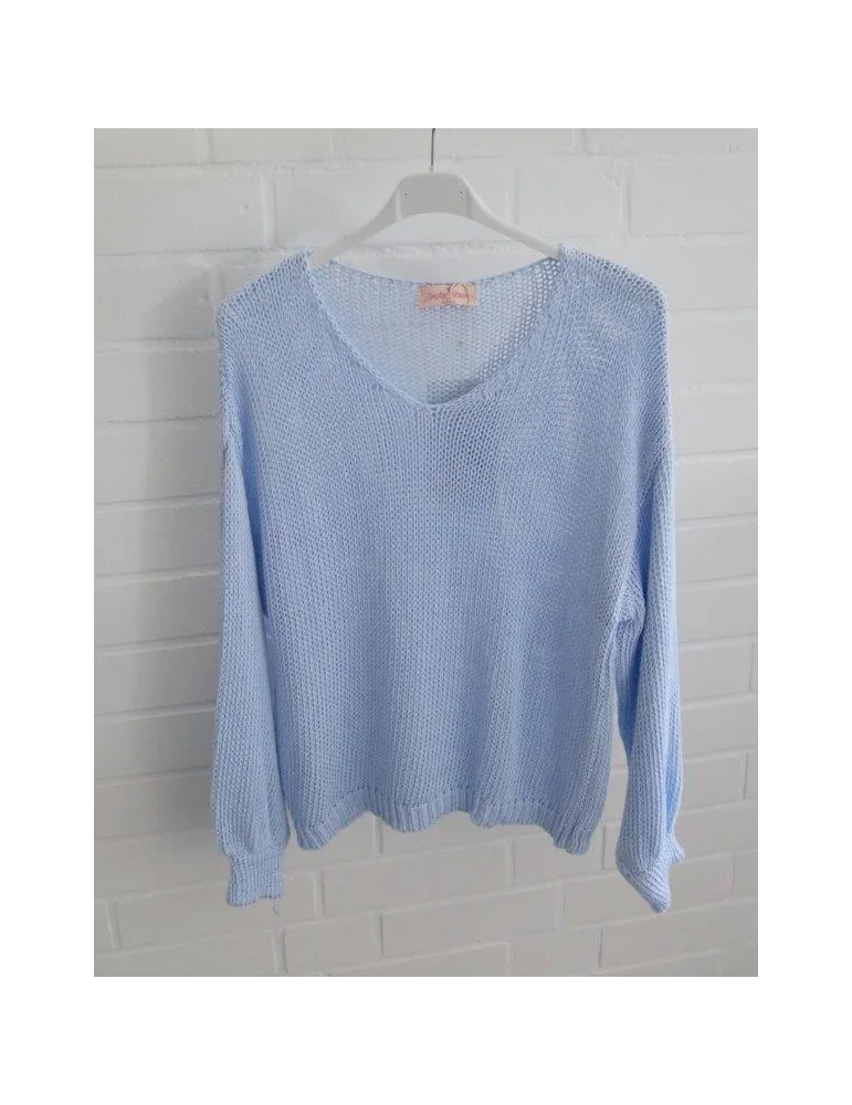 Hellblau gestrickter Damenpullover mit V-Ausschnitt auf Kleiderbügel vor weißer Wand