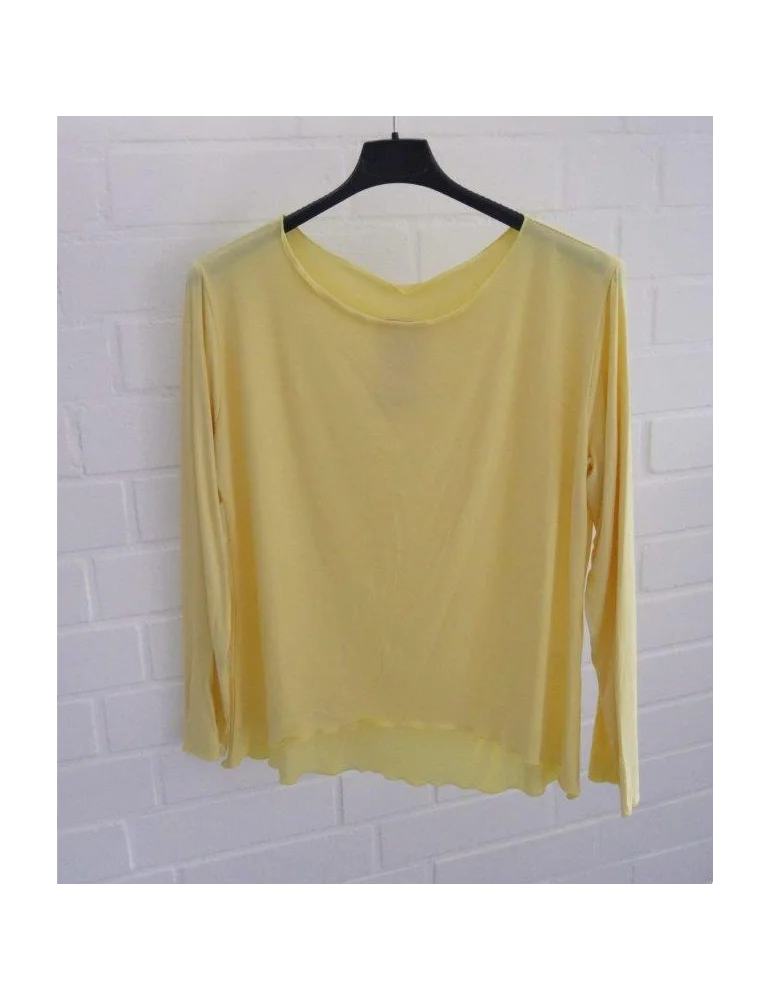 Gelbes langarm Shirt mit Rundhalsausschnitt vor weißer Wand