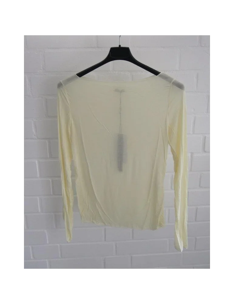 Gelbes Longsleeve mit Rundhalsausschnitt vor weißer Wand