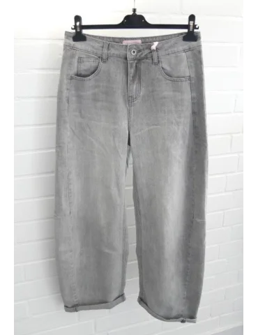 Graue Balloon Jeans mit seitlichen Einsätzen und Umschlägen vor weißer Wand