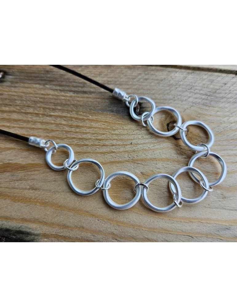 Kurze Modescmuckkette für Damen mit schwarzem Textilband und eingearbeiteten silberfarben, matten Ringen