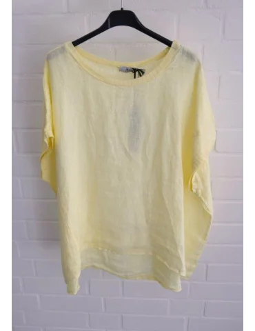 Gelbes Leinen T-Shirt mit Ziernähten vor weißer Wand