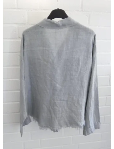 Rückansicht Hellgraue Damen Leinenbluse mit Brusttaschen und ausgefranstem Saum vor weißer Wand.
