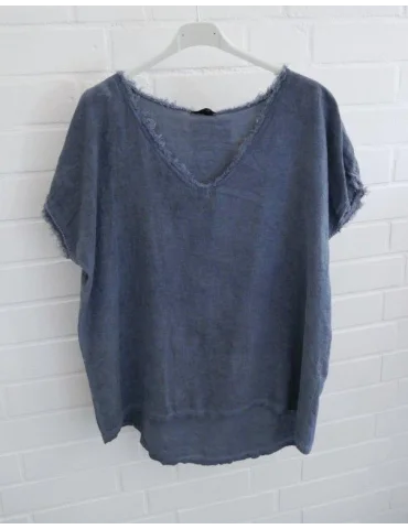 Blaues Damen Shirt mit V-Ausschnitt und ausgefransten Kanten vor weißer Wand.
