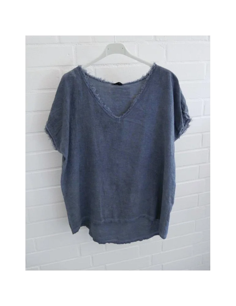 Blaues Damen Shirt mit V-Ausschnitt und ausgefransten Kanten vor weißer Wand.