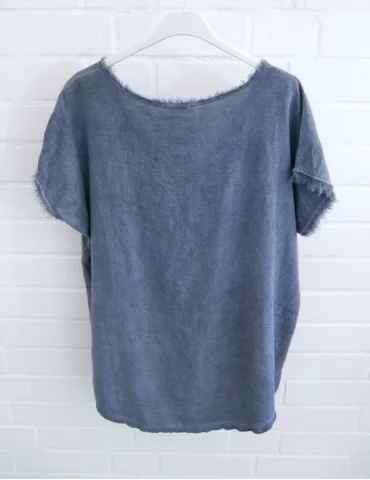 Rückansicht Blaues Damen Shirt mit V-Ausschnitt und ausgefransten Kanten vor weißer Wand.