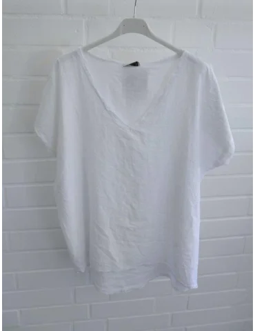 Weißes Damen Shirt mit V-Ausschnitt und ausgefransten Kanten vor weißer Wand