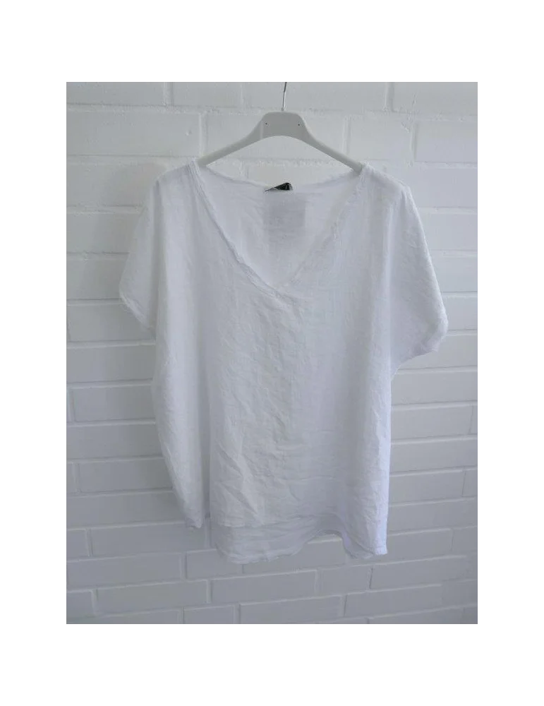 Weißes Damen Shirt mit V-Ausschnitt und ausgefransten Kanten vor weißer Wand