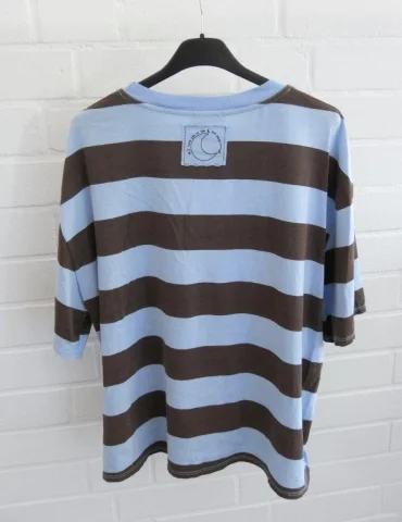 Rückansicht Hellblau und braun gestreiftes Damen Oversized T-Shirt hängend vor weißer Ziegelwand