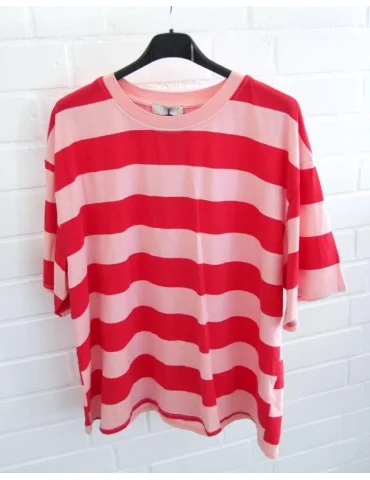 Rose und Rot gestreiftes Damen Oversized T-Shirt hängend vor weißer Ziegelwand