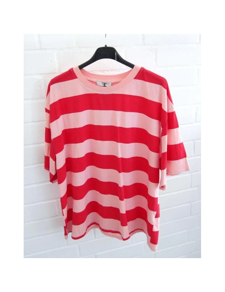 Rose und Rot gestreiftes Damen Oversized T-Shirt hängend vor weißer Ziegelwand