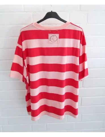 Rückansicht Rose und Rot gestreiftes Damen Oversized T-Shirt hängend vor weißer Ziegelwand