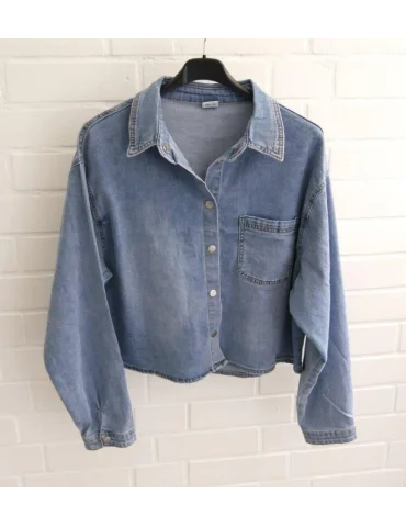 Kurzes kastiges Jeanshemd für Damen vor weißer Wand