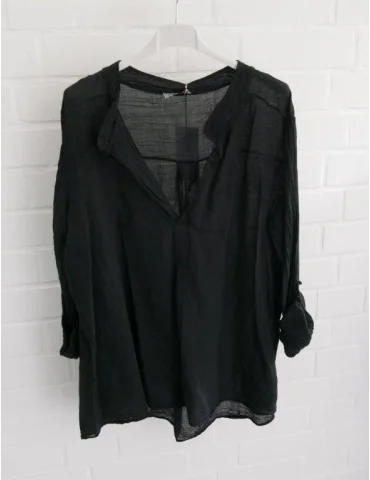 Schwarze Damenbluse mit langen Ärmeln vor weißer Wand