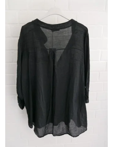 Rückansicht Schwarze Damenbluse mit langen Ärmeln vor weißer Wand