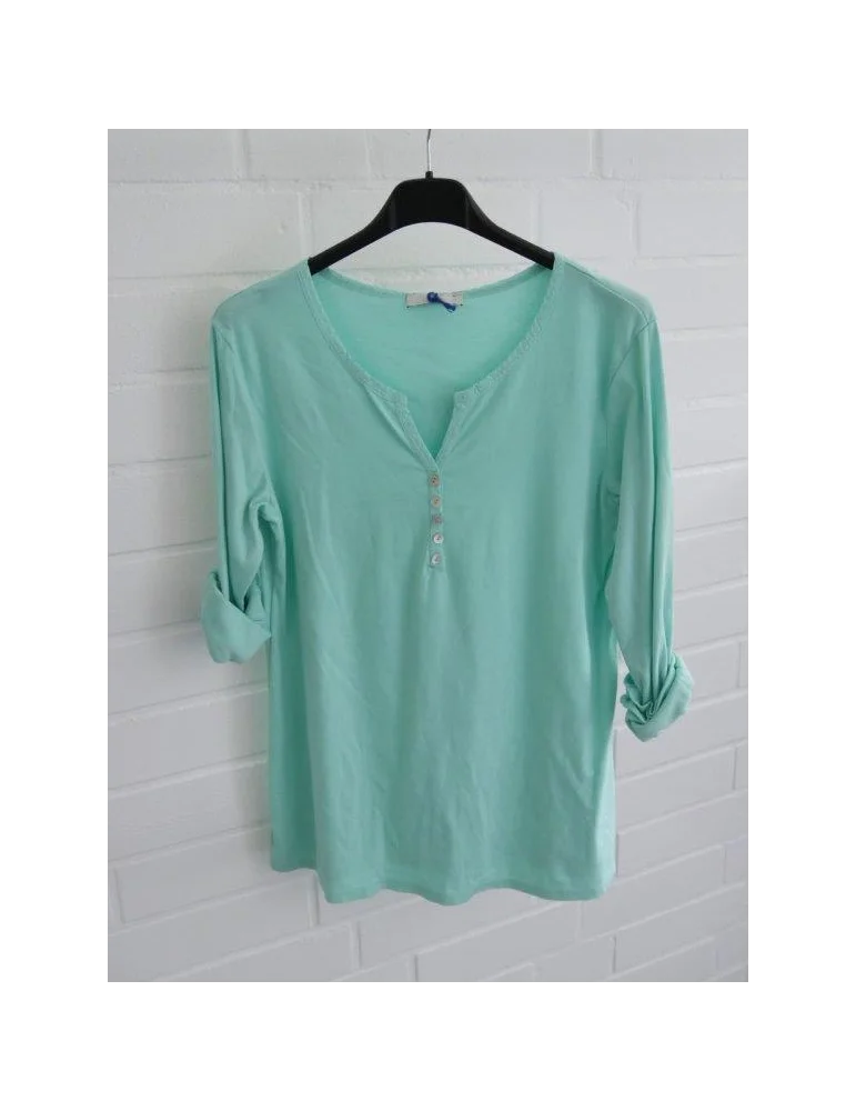 Mintfarbenes Henley Shirt mit langen Ärmeln vor weißer Wand