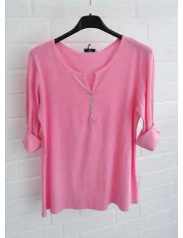 Pinkes Shirt mit Knopfleiste und langen Ärmeln vor weißer Wand