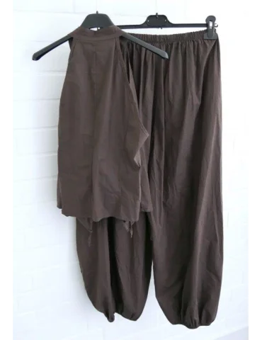 Braune Hose und Top auf Kleiderbügeln vor weißer Wand von hinten