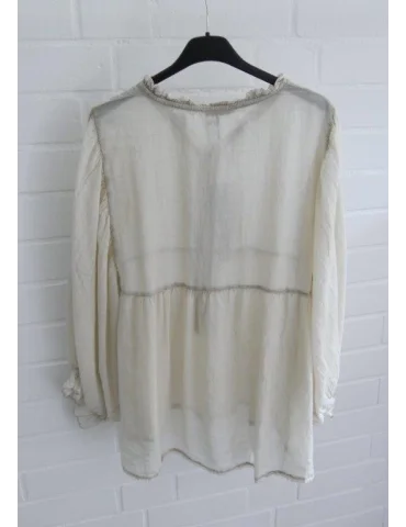 Rückansicht beige Bluse mit Fledermausärmeln vor weißer Wand