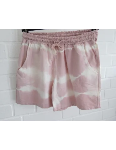 Rose cremefarbene Shorts mit Batikmuster vor weißer Wand