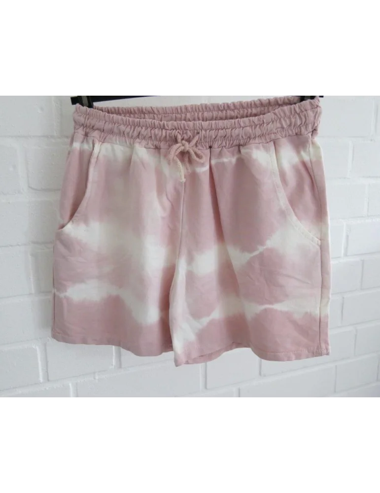 Rose cremefarbene Shorts mit Batikmuster vor weißer Wand