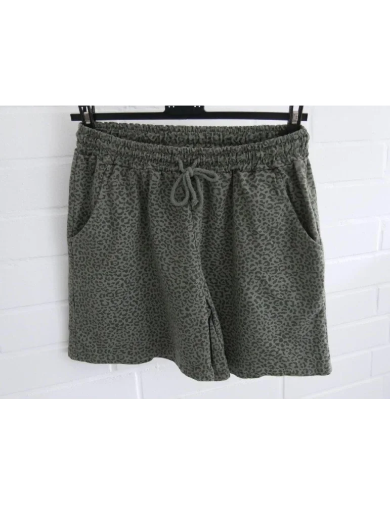 Shorts in oliv mit Leoprint auf Kleiderbügel vor weißer Wand