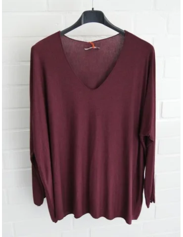 Weinrotes Shirt mit V-Ausschnitt für Damen vor weißer Wand