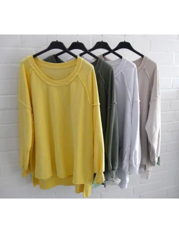 Bunte Sweatshirts auf einer Stange vor weißer Wand