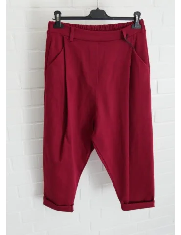 Weinrote Baggy Hose für Damen vor weißer Wand