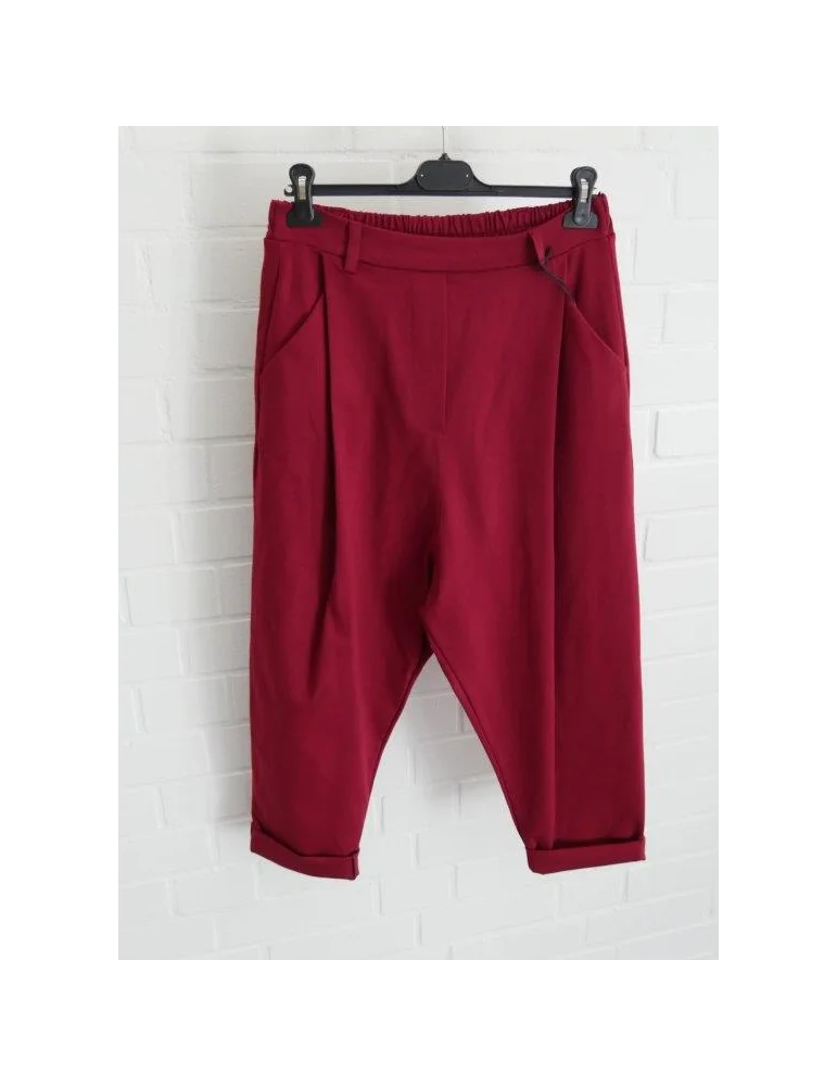 Weinrote Baggy Hose für Damen vor weißer Wand