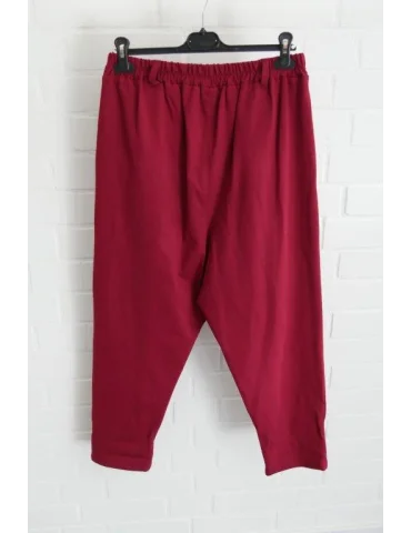 Weinrote Baggy Hose für Damen vor weißer Wand von Hinten