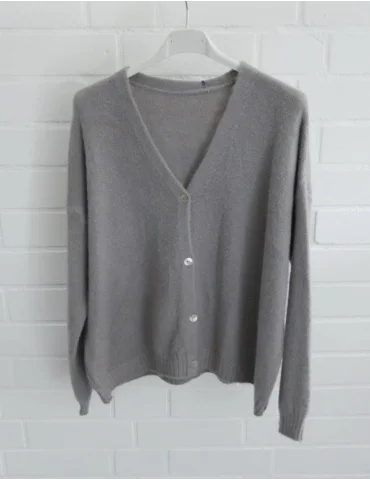 Graue Damen Strickjacke mit Knöpfen und V-Ausschnitt vor weißer Wand