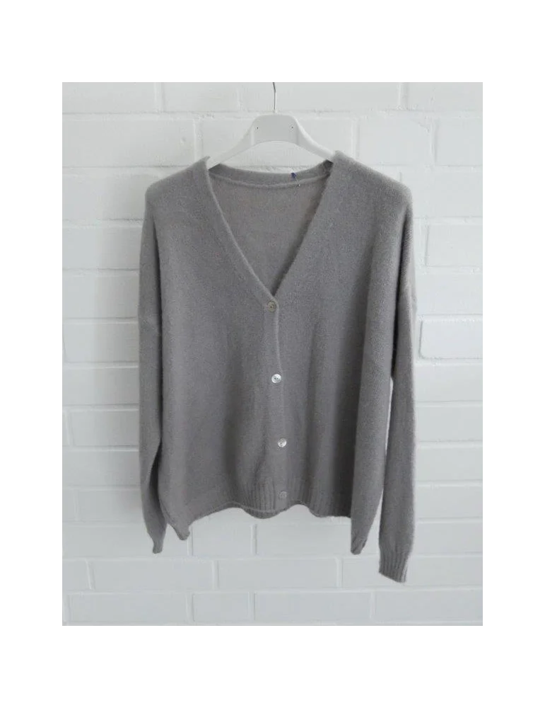 Graue Damen Strickjacke mit Knöpfen und V-Ausschnitt vor weißer Wand