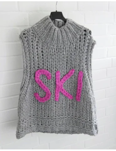 Grauer Grobstrick-Pullover ohne Ärmel mit pinkem SKI-Schriftzug an einem Bügel
