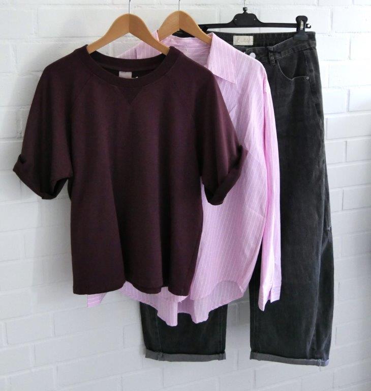 Anthrazitfarbene jeans mit rose gestreifter Bluse und kurzarm Sweatie in aubergine vor weißer Wand