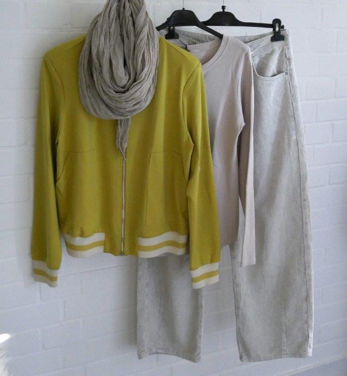 Beige Cordhose, Beiges Longsleeve, Senffarbener Blouson und beiger Schal hängend vor weißer Wand