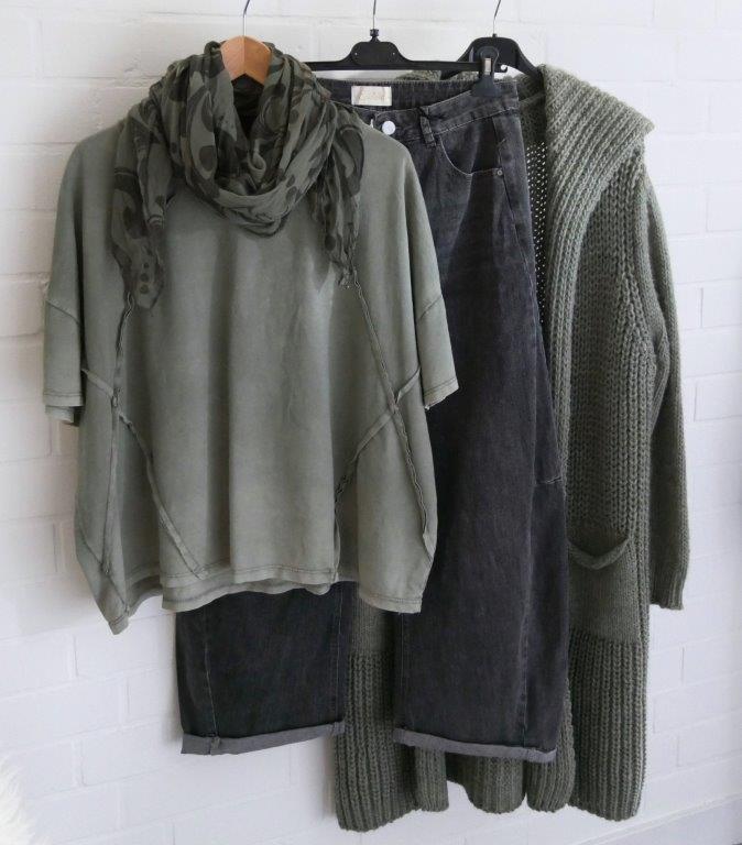 Graue O-Shape Jeans, Olivgrünes kurzarm Shirt, olivgrüne Grobstrickjacke und passender Schal hängend vor weißer Wand